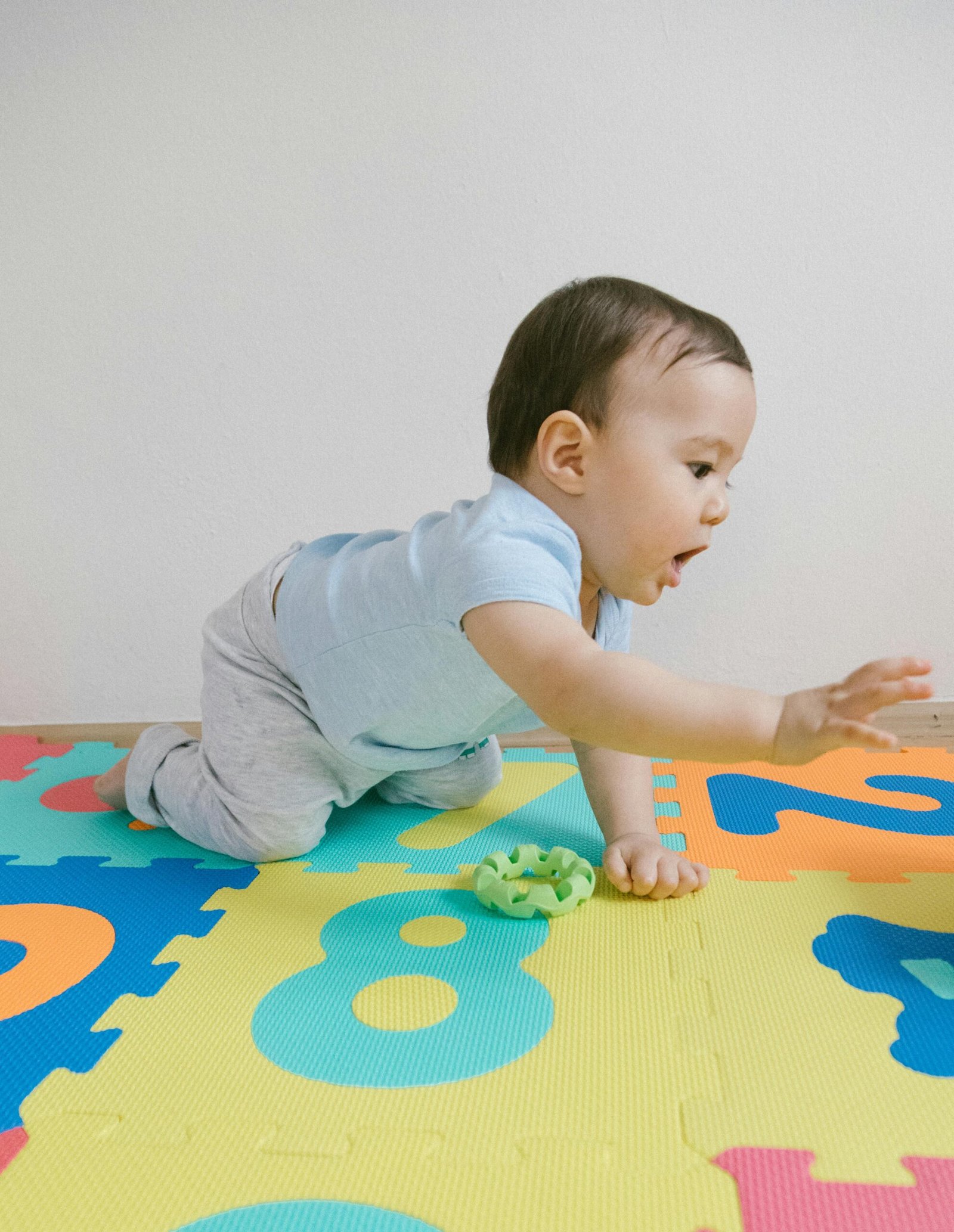 Adorable baby boy crawling on a vibrant puzzle mat indoors, showcasing childhood innocence and play.